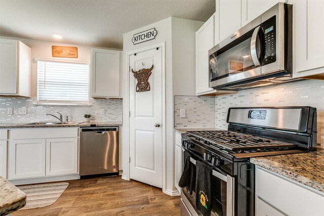 1007 Cozumel Emerald, San Antonio, TX 78253 - kitchen featuring appliances with stainless steel finishes, white cabinetry, light wood-type flooring, and decorative backsplash