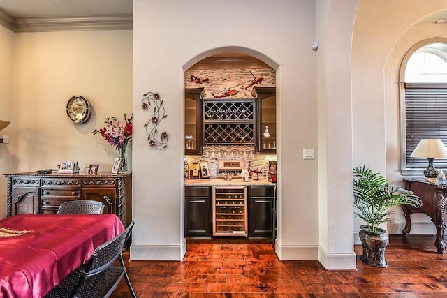 12349 Tramonto Dr, Conroe, TX 77304 - indoor dry bar with beverage cooler, dark wood-style flooring, crown molding, arched walkways, and backsplash