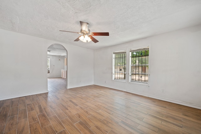 3822 Wipprecht St, Houston, TX 77026 - empty room with a ceiling fan, arched walkways, wood finished floors, and a textured ceiling