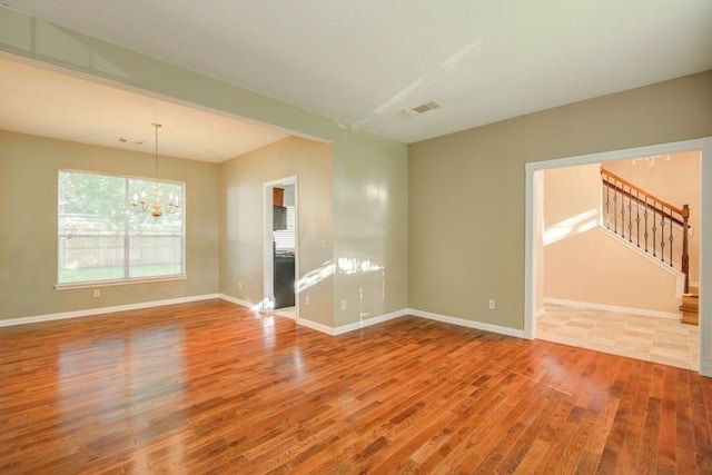2917 Veva Dr, Pearland, TX 77584 - empty room featuring wood finished floors, a chandelier, and stairs