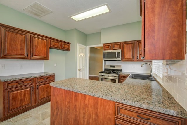 2917 Veva Dr, Pearland, TX 77584 - kitchen with appliances with stainless steel finishes, brown cabinets, decorative backsplash, and a peninsula