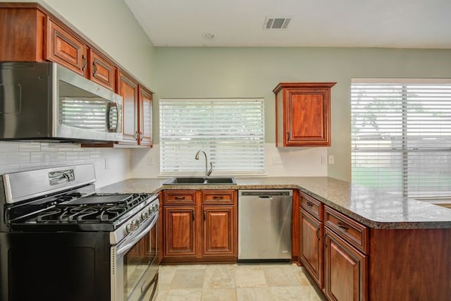 2917 Veva Dr, Pearland, TX 77584 - kitchen featuring appliances with stainless steel finishes, a peninsula, and brown cabinets