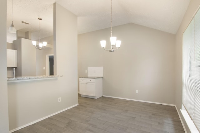 16822 Applecross Ln, Houston, TX 77084 - unfurnished dining area featuring a chandelier, wood finished floors, vaulted ceiling, and a textured ceiling