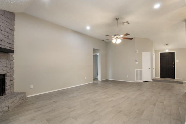 16822 Applecross Ln, Houston, TX 77084 - unfurnished living room with lofted ceiling, a fireplace, a ceiling fan, wood finished floors, and a textured ceiling