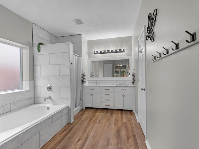 13923 Roanoke Falls Dr, Cypress, TX 77429 - full bathroom featuring tiled shower, double vanity, a garden tub, and wood finished floors