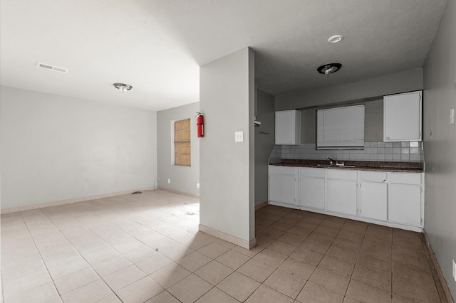 14504 Corpus Christi St Unit 4, Houston, TX 77015 - kitchen featuring dark countertops, white cabinetry, light tile patterned floors, and backsplash