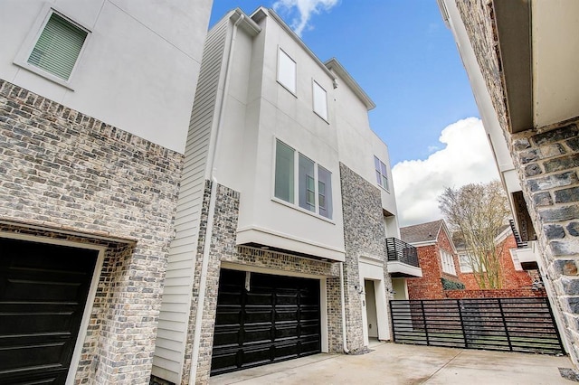 1405 Indiana St Unit B, Houston, TX 77006 - view of front of house featuring a garage, concrete driveway, stucco siding, and stone siding