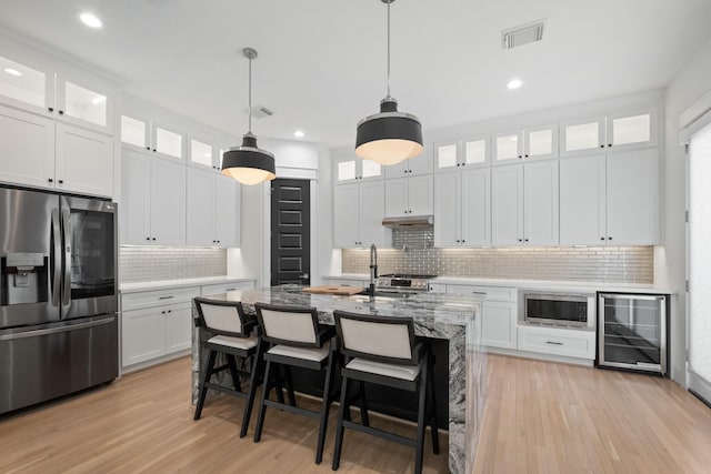 1405 Indiana St Unit B, Houston, TX 77006 - kitchen with appliances with stainless steel finishes, beverage cooler, decorative backsplash, under cabinet range hood, and light wood finished floors