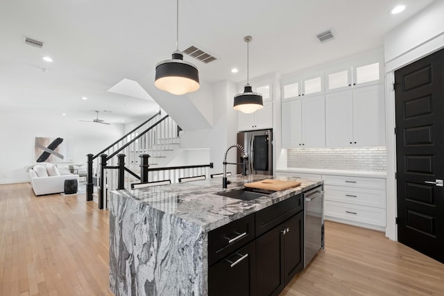 1405 Indiana St Unit B, Houston, TX 77006 - kitchen featuring stainless steel appliances, backsplash, light wood-style flooring, white cabinets, and recessed lighting