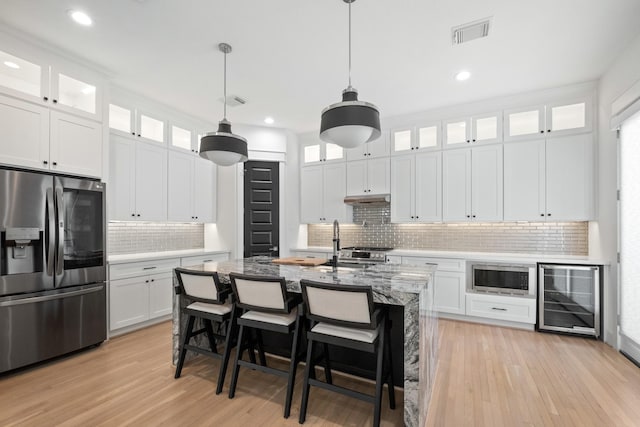 1405 Indiana St Unit B, Houston, TX 77006 - kitchen featuring appliances with stainless steel finishes, wine cooler, tasteful backsplash, under cabinet range hood, and light wood finished floors