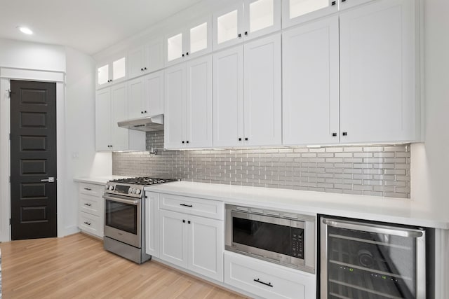 1405 Indiana St Unit B, Houston, TX 77006 - kitchen with beverage cooler, stainless steel appliances, under cabinet range hood, light countertops, and white cabinetry