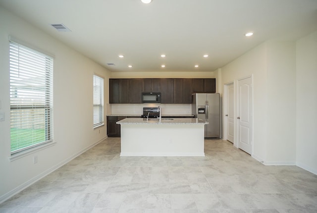 4615 Sabine Creek Way, Katy, TX 77449 - kitchen with stainless steel refrigerator with ice dispenser, black microwave, dark brown cabinets, an island with sink, and recessed lighting