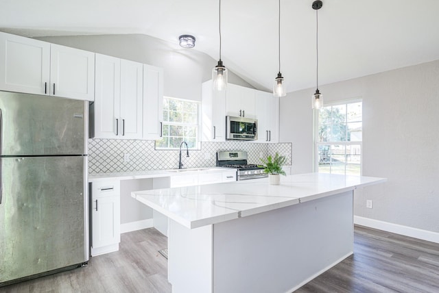 1111 Robinson St, Alvin, TX 77511 - kitchen featuring stainless steel appliances, vaulted ceiling, light wood-style floors, white cabinets, and decorative backsplash