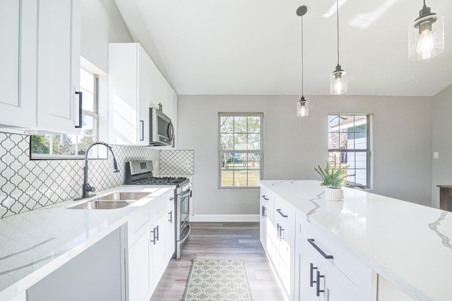 1111 Robinson St, Alvin, TX 77511 - kitchen featuring appliances with stainless steel finishes, light wood finished floors, light stone countertops, tasteful backsplash, and white cabinets