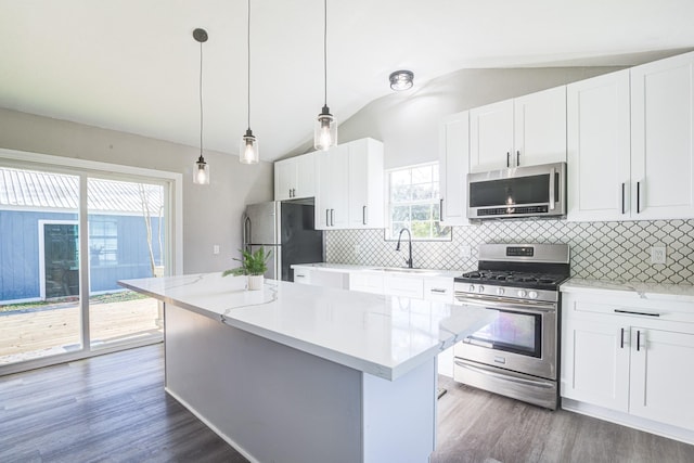 1111 Robinson St, Alvin, TX 77511 - kitchen featuring stainless steel appliances, vaulted ceiling, a kitchen island, tasteful backsplash, and dark wood-style floors