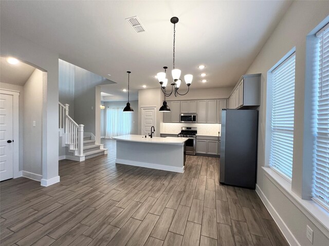 18518 Parkland Xing, Cypress, TX 77433 - kitchen with appliances with stainless steel finishes, dark wood finished floors, tasteful backsplash, an island with sink, and gray cabinets