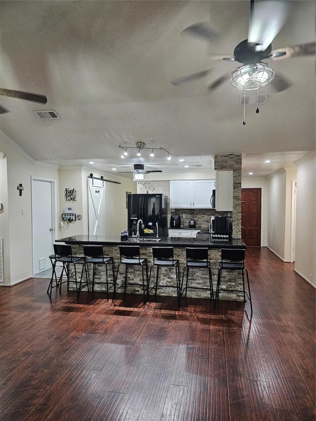 19423 Quiet Brook Dr, Houston, TX 77084 - kitchen featuring ceiling fan, a barn door, black refrigerator with ice dispenser, dark countertops, and dark wood finished floors