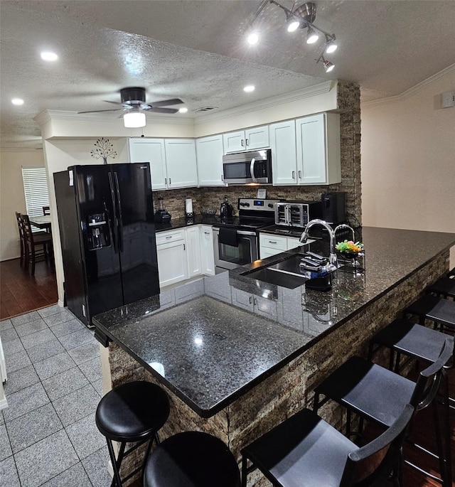 19423 Quiet Brook Dr, Houston, TX 77084 - kitchen with stainless steel appliances, ornamental molding, a textured ceiling, a peninsula, and a breakfast bar