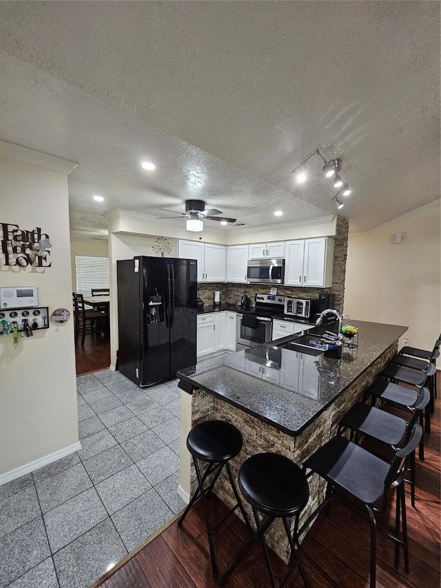 19423 Quiet Brook Dr, Houston, TX 77084 - kitchen with appliances with stainless steel finishes, a peninsula, a textured ceiling, a kitchen bar, and backsplash