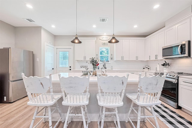 807 Ave J Pl, Conroe, TX 77301 - kitchen with appliances with stainless steel finishes, a kitchen island, light countertops, light wood finished floors, and recessed lighting