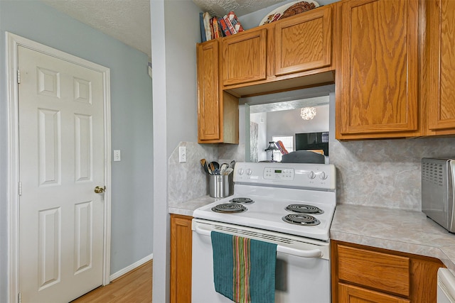 7806 Burgess Rd, Hitchcock, TX 77563 - kitchen featuring electric stove, light countertops, decorative backsplash, and light wood finished floors