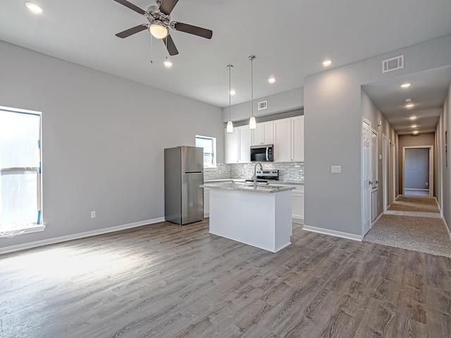 8206 Tower St, Houston, TX 77088 - kitchen with appliances with stainless steel finishes, a kitchen island with sink, dark wood-style flooring, white cabinetry, and recessed lighting