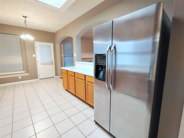 3511 Glenhill Dr, Pearland, TX 77584 - kitchen with stainless steel fridge, light tile patterned flooring, light countertops, arched walkways, and pendant lighting