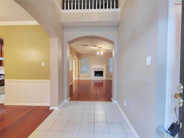 3511 Glenhill Dr, Pearland, TX 77584 - foyer entrance featuring ceiling fan, arched walkways, light wood-style flooring, a tile fireplace, and ornamental molding