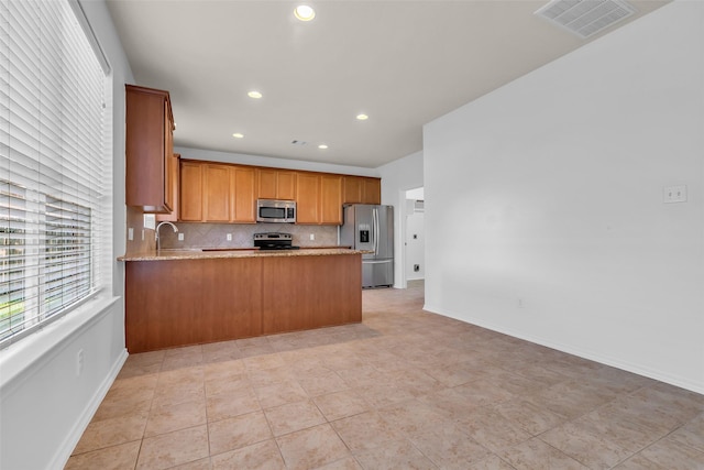3502 Avalon Spring Ln, Spring, TX 77386 - kitchen featuring a peninsula, tasteful backsplash, stainless steel appliances, recessed lighting, and brown cabinetry