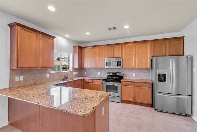 3502 Avalon Spring Ln, Spring, TX 77386 - kitchen featuring stainless steel appliances, a peninsula, light stone counters, tasteful backsplash, and brown cabinets