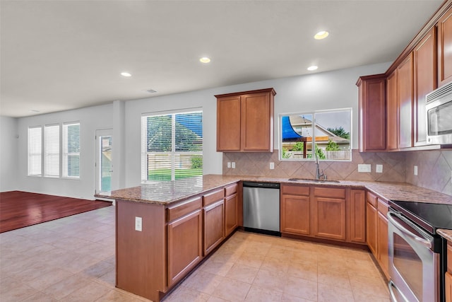 3502 Avalon Spring Ln, Spring, TX 77386 - kitchen with brown cabinets, light stone countertops, a peninsula, stainless steel appliances, and tasteful backsplash