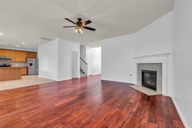 3502 Avalon Spring Ln, Spring, TX 77386 - unfurnished living room with light wood-style flooring, ceiling fan, stairs, a tile fireplace, and recessed lighting