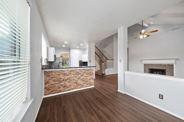 1123 Woodley Bnd, Sugar Land, TX 77479 - kitchen with dark countertops, a fireplace, dark wood-type flooring, white cabinets, and a ceiling fan