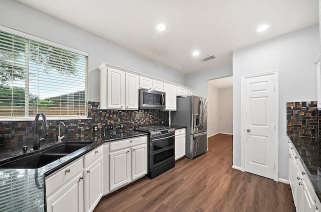 1123 Woodley Bnd, Sugar Land, TX 77479 - kitchen featuring appliances with stainless steel finishes, decorative backsplash, white cabinetry, dark wood-type flooring, and recessed lighting