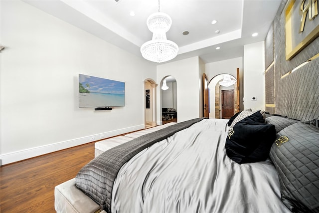 701 W Friar Tuck Ln, Houston, TX 77024 - bedroom featuring arched walkways, recessed lighting, wood finished floors, a chandelier, and a tray ceiling