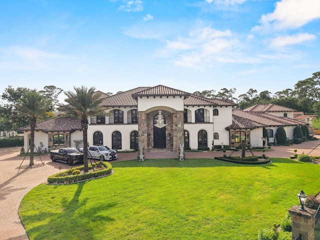 701 W Friar Tuck Ln, Houston, TX 77024 - mediterranean / spanish-style house with stucco siding, driveway, stone siding, a front lawn, and a tile roof