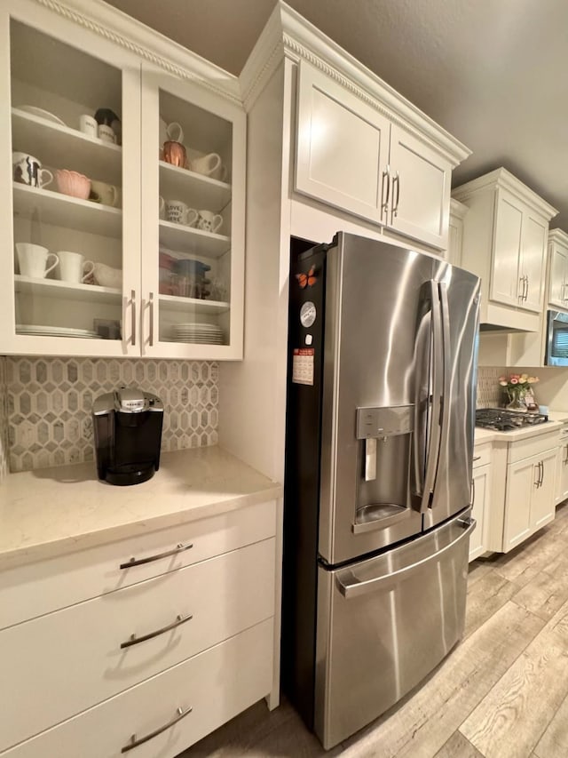 15814 Weston Ridge Dr, Humble, TX 77346 - kitchen featuring appliances with stainless steel finishes, decorative backsplash, light wood-style floors, glass insert cabinets, and white cabinets