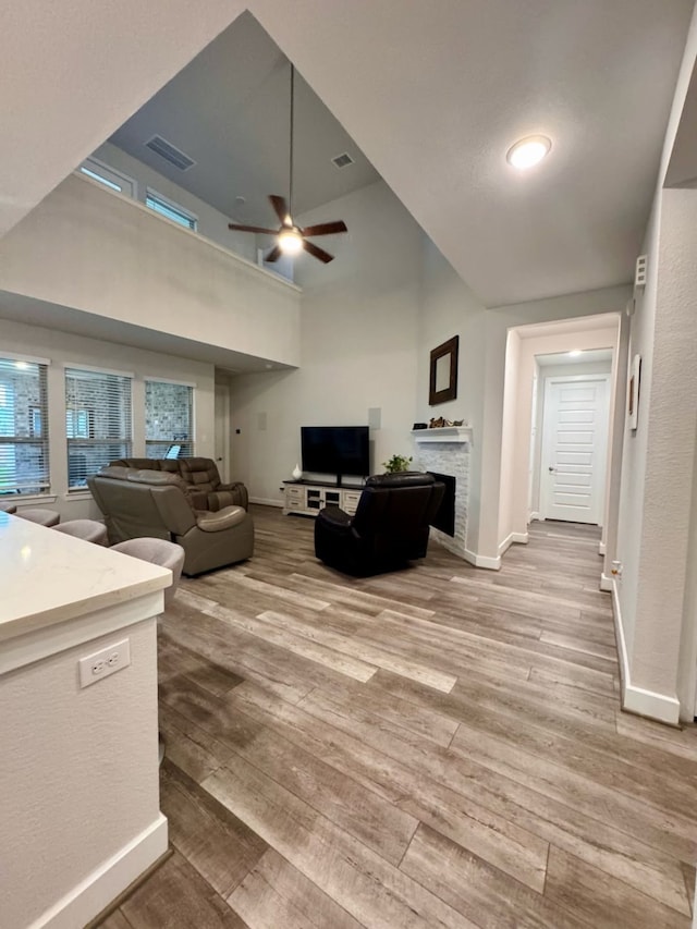 15814 Weston Ridge Dr, Humble, TX 77346 - living area featuring light wood finished floors, a ceiling fan, a fireplace, and a high ceiling