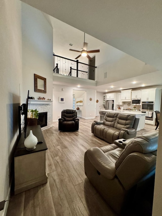 15814 Weston Ridge Dr, Humble, TX 77346 - living area with light wood-style flooring, a ceiling fan, a high ceiling, and a stone fireplace