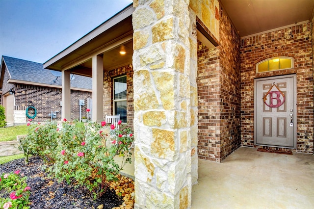 12223 Antilles Ln, Conroe, TX 77304 - view of exterior entry with brick siding, covered porch, stone siding, and roof with shingles