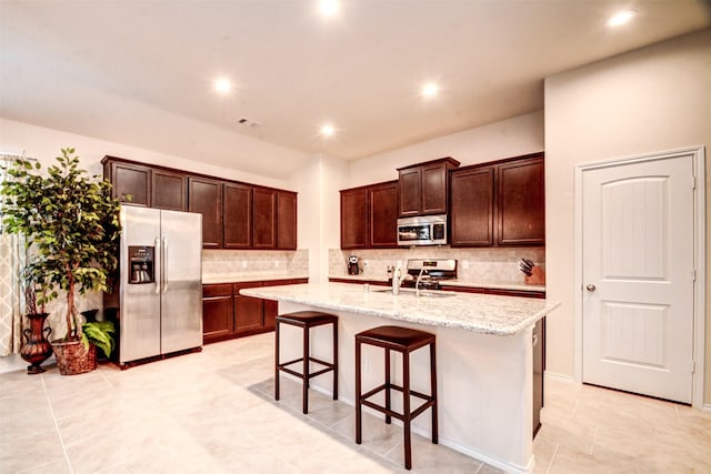 12223 Antilles Ln, Conroe, TX 77304 - kitchen featuring stainless steel appliances, tasteful backsplash, an island with sink, light stone countertops, and recessed lighting