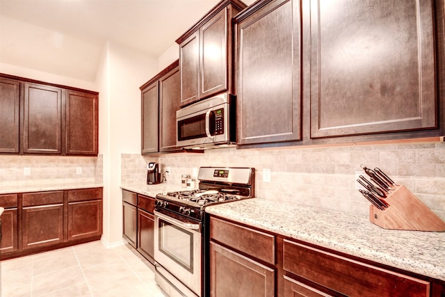 12223 Antilles Ln, Conroe, TX 77304 - kitchen with appliances with stainless steel finishes, decorative backsplash, light stone counters, light tile patterned floors, and dark brown cabinetry