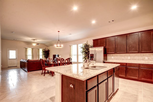 12223 Antilles Ln, Conroe, TX 77304 - kitchen featuring backsplash, stainless steel appliances, a center island with sink, light stone counters, and hanging light fixtures