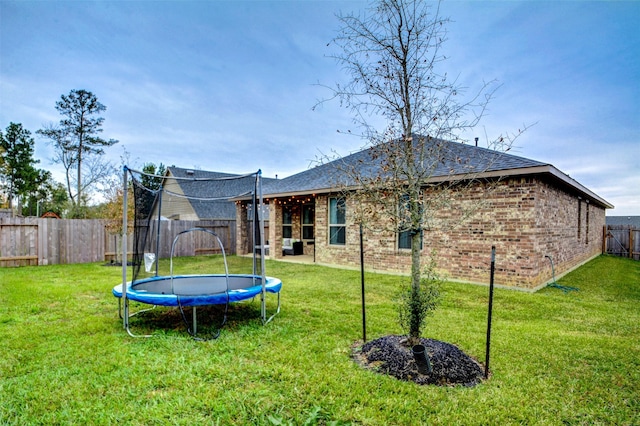 12223 Antilles Ln, Conroe, TX 77304 - rear view of house with a trampoline, brick siding, and a fenced backyard
