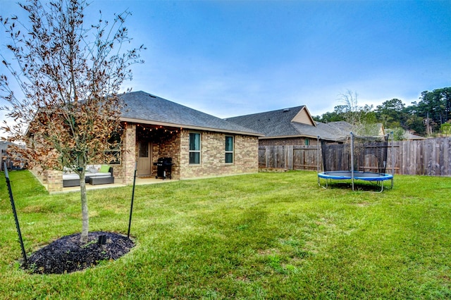12223 Antilles Ln, Conroe, TX 77304 - back of house featuring roof with shingles, a fenced backyard, brick siding, and a trampoline