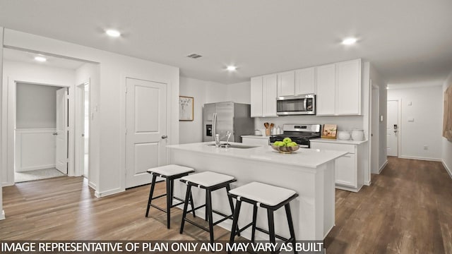 23748 Patchouli Terrace Dr, Splendora, TX 77372 - kitchen with dark wood-style floors, stainless steel appliances, a kitchen island with sink, white cabinets, and light countertops
