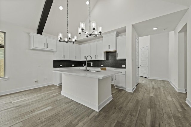 16710 Yaklin Meadow Ct, Humble, TX 77346 - kitchen featuring a chandelier, backsplash, an island with sink, light wood-style flooring, and high vaulted ceiling