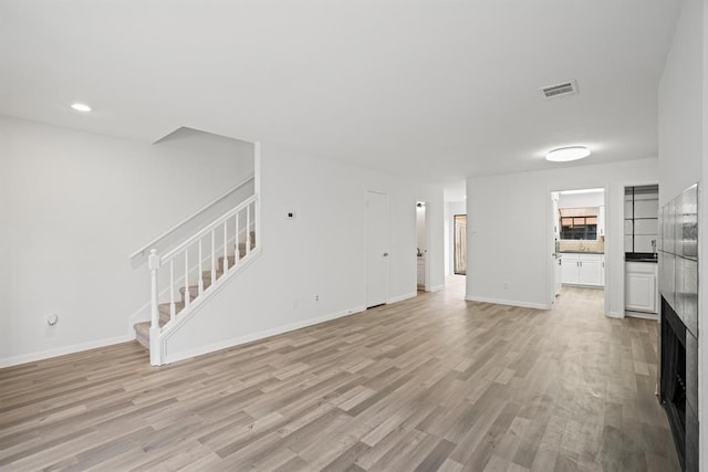 9901 Sharpcrest St Unit K-3, Houston, TX 77036 - unfurnished living room with stairway, light wood-style flooring, a fireplace, and recessed lighting