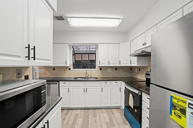 9901 Sharpcrest St Unit K-3, Houston, TX 77036 - kitchen featuring appliances with stainless steel finishes, white cabinets, light wood-style floors, decorative backsplash, and under cabinet range hood