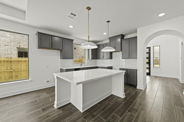 16738 Yaklin Meadow Ct, Humble, TX 77346 - kitchen featuring arched walkways, dark wood-style flooring, tasteful backsplash, a kitchen island, and recessed lighting